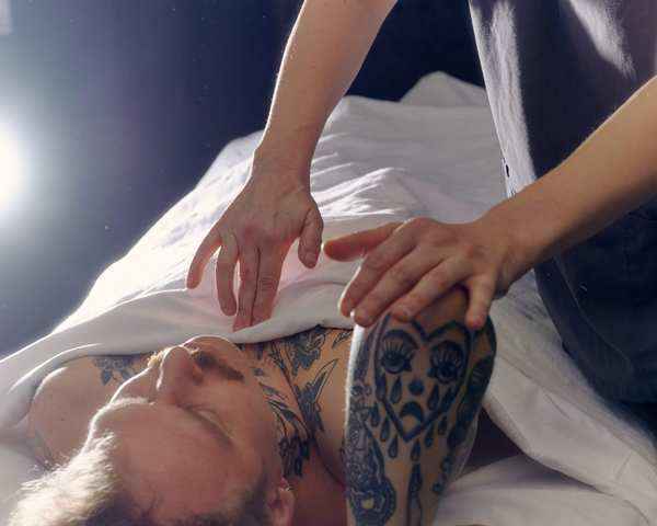 A massage therapist stretches an arm over a client's head