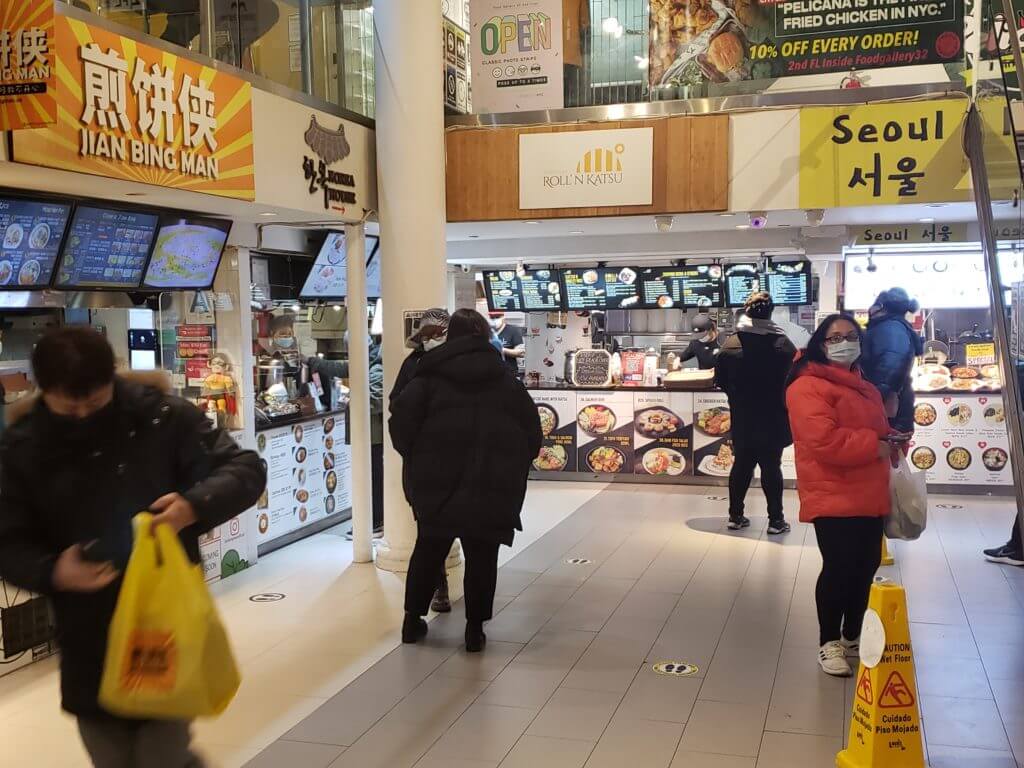 Several masked shoppers waiting in line for food from Koreatown's Food Galler 32 in Manhattan NYC