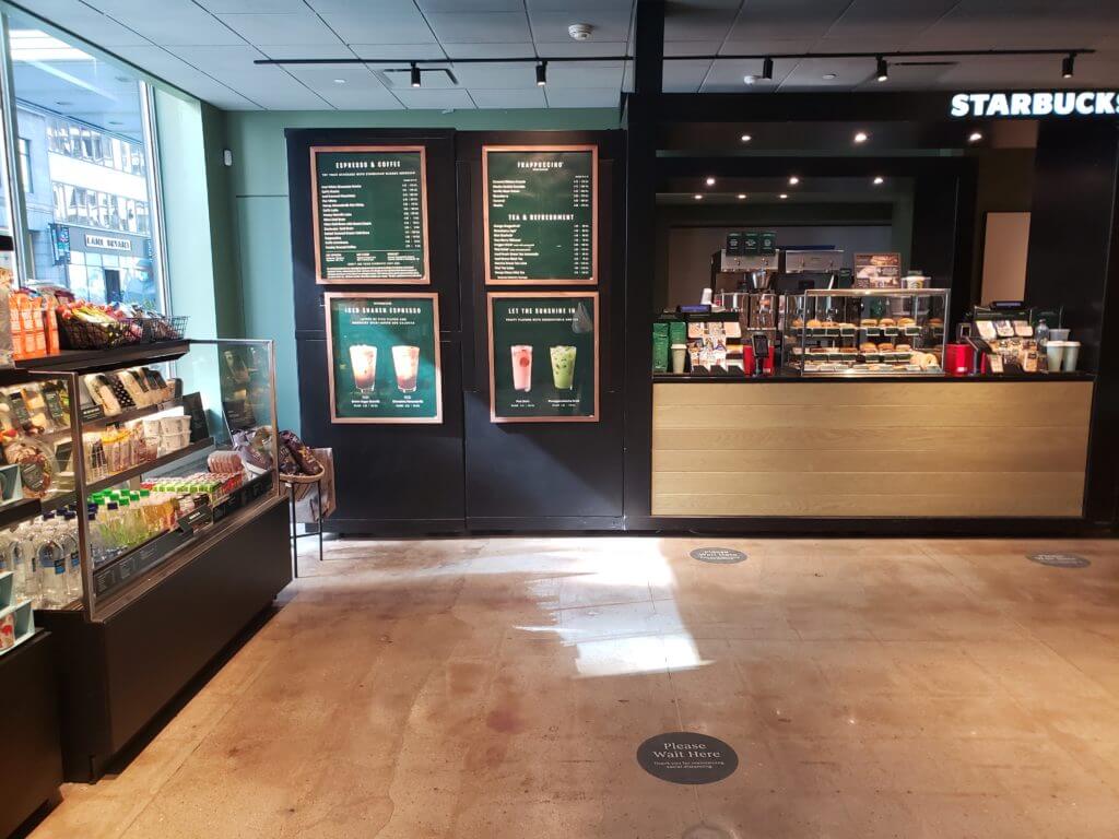 Interiror of the Empire State Building's new Starbucks location. Left side shoes various nacks and meals, center shows coffe menu and wooden counter